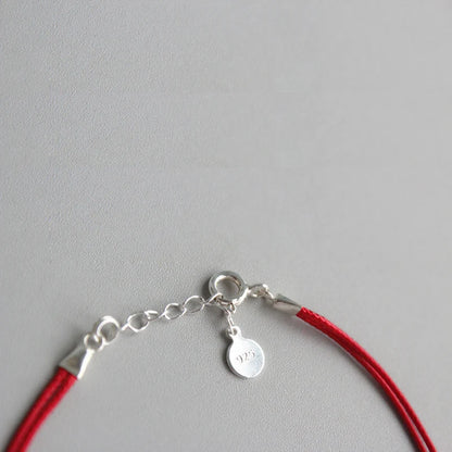 Armband Fini - Seitenansicht zeigt die Kombination aus Silber und rotem Faden" "Armband Fini aus 925 Silber - Draufsicht mit geometrischem Muster