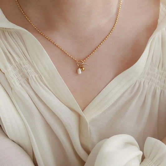 Vergoldete Halskette aus Titan mit Perle getragen | kurzer Halsschmuck für Damen | schlichter Perlenschmuck